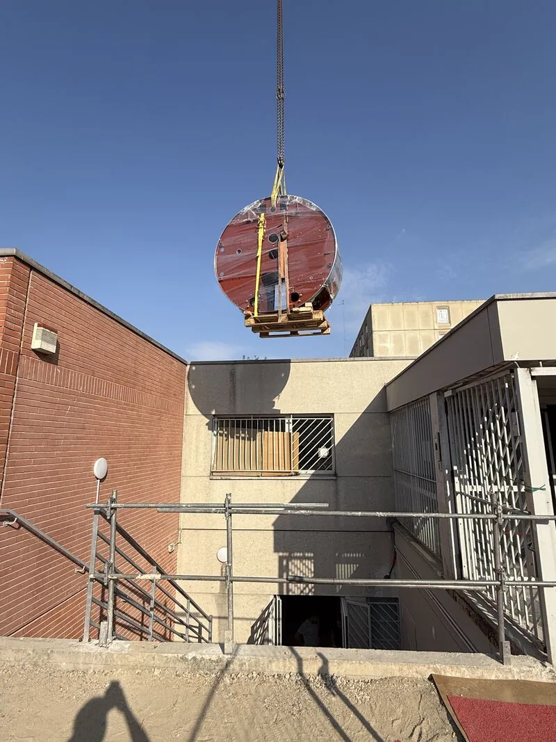 Wrapped gantry being lifted by crane outside the building — Bobigny – IRHE