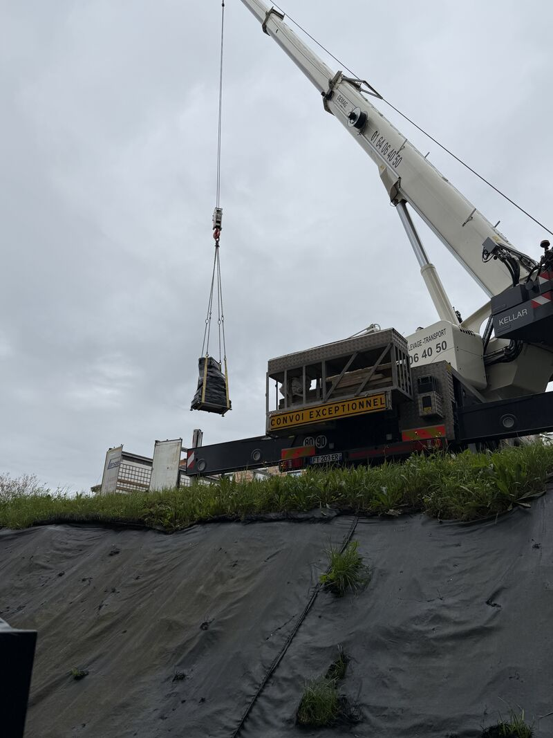 Wrapped component lifted by crane in front of the building — Argenteuil