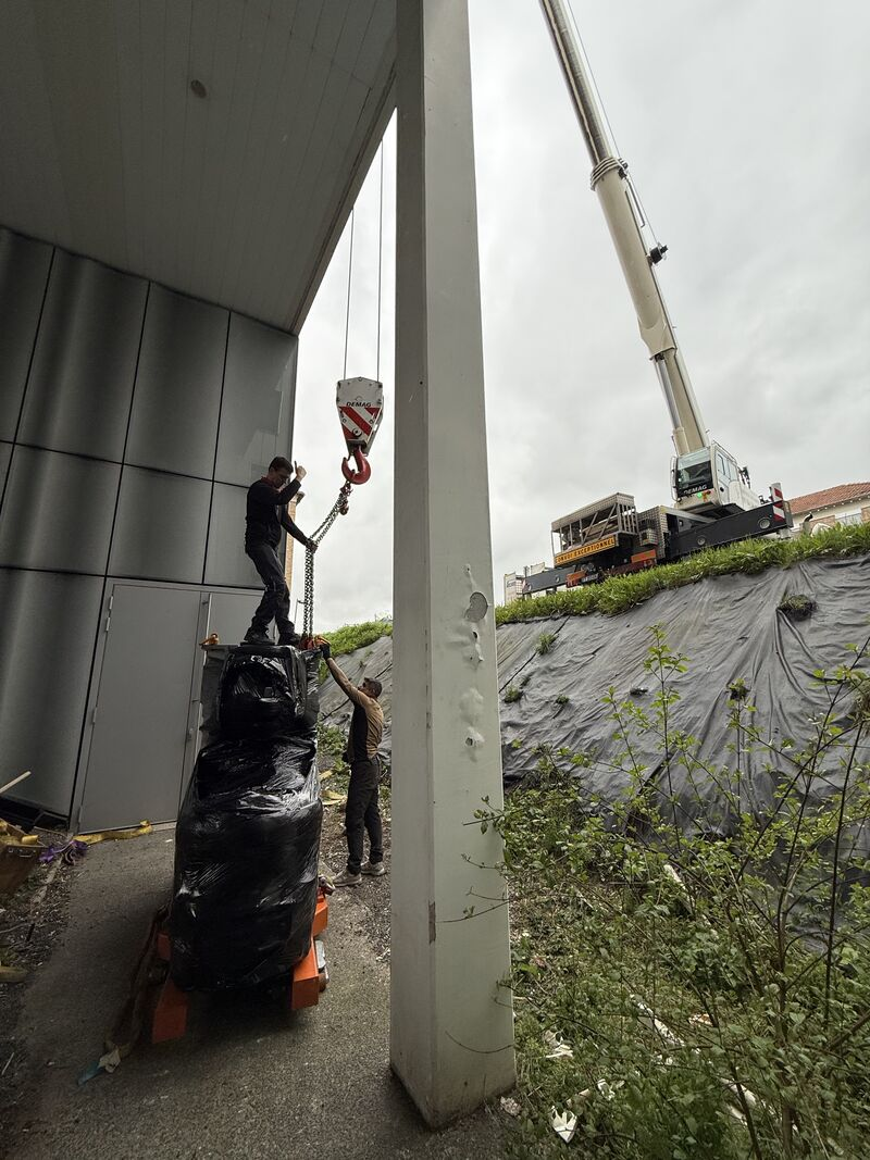 Team working on the lifting attachment of the wrapped unit — Argenteuil