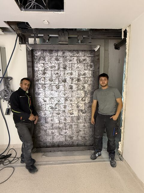 Two team members beside the metal door leaf — Gaziantep