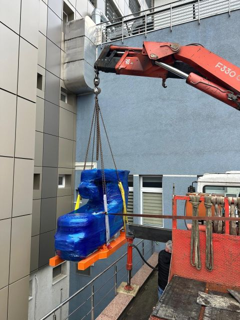 Wrapped unit being moved by crane in the outdoor work area — Iași