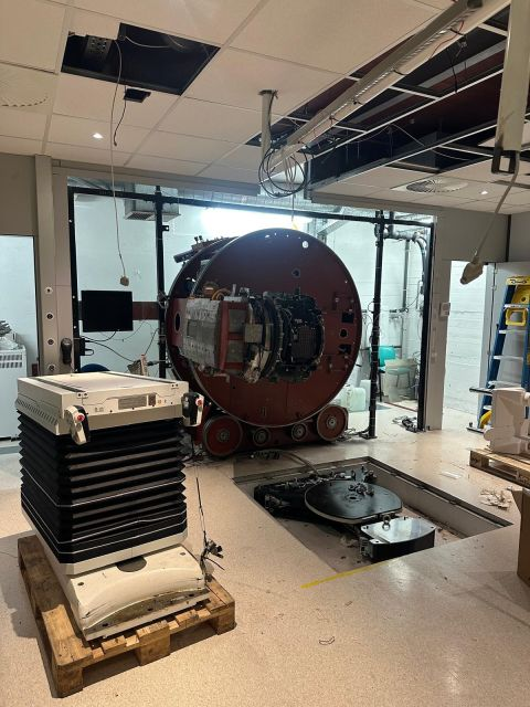 Detached table and equipment parts in front of the exposed gantry — Saint-Luc