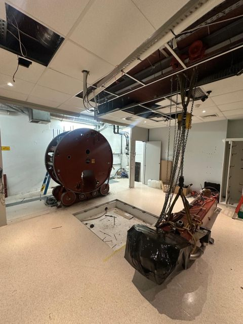 Partly wrapped LINAC arm attached to a hoist — Saint-Luc